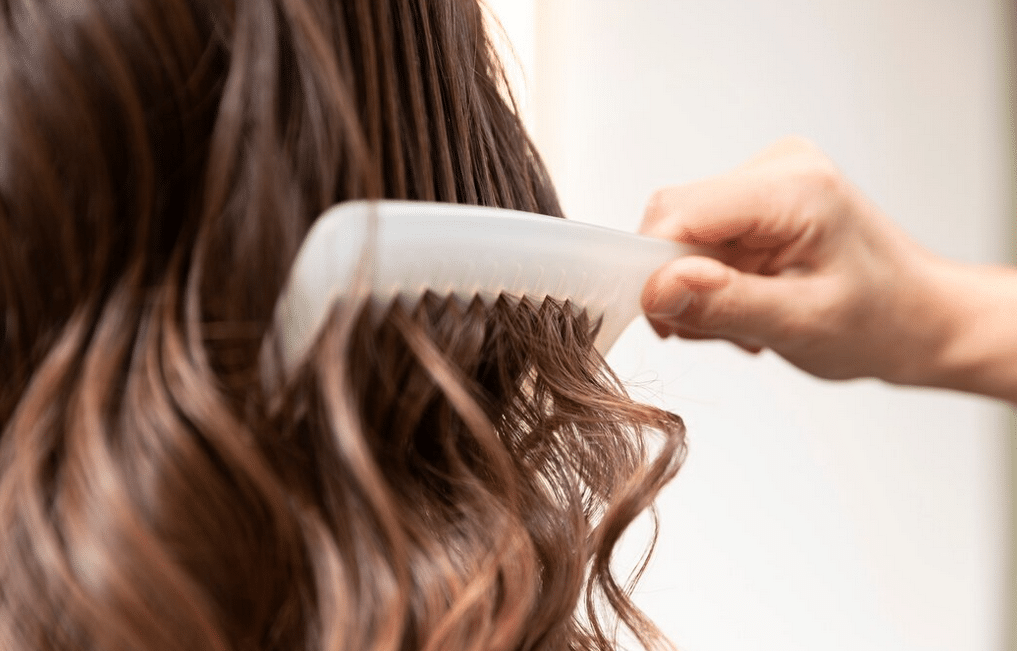 saç kremi sürmüş bir kadın saçını tarıyor